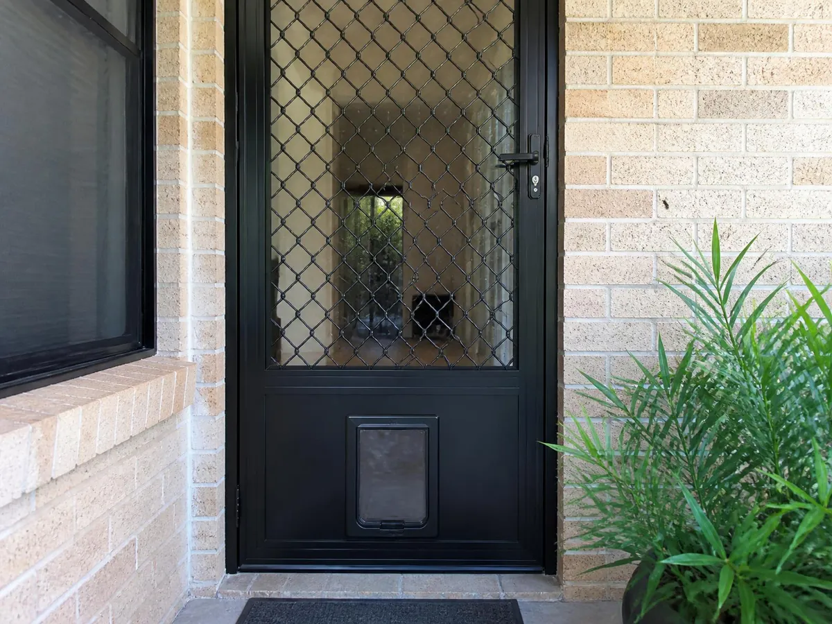 Pet door neatly integrated into the lower panel of a black security screen door